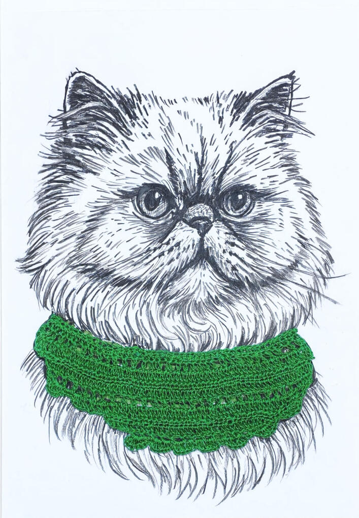 Gato persa con complemento de crochet color verde.