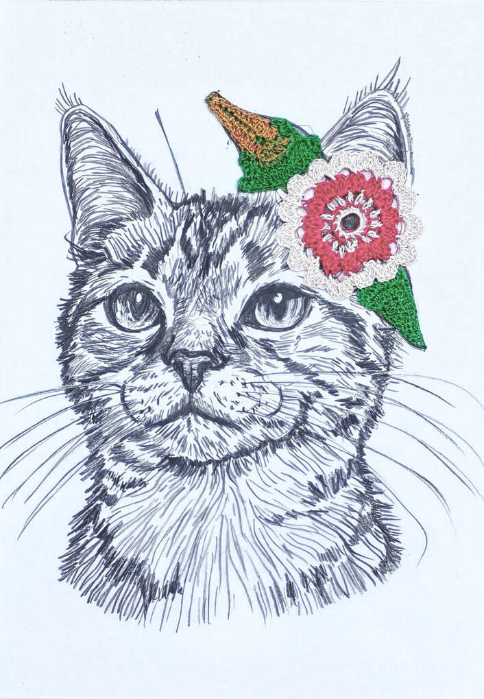 Gato con complemento crochet flor tonos rosas con hojas verdes en oreja.